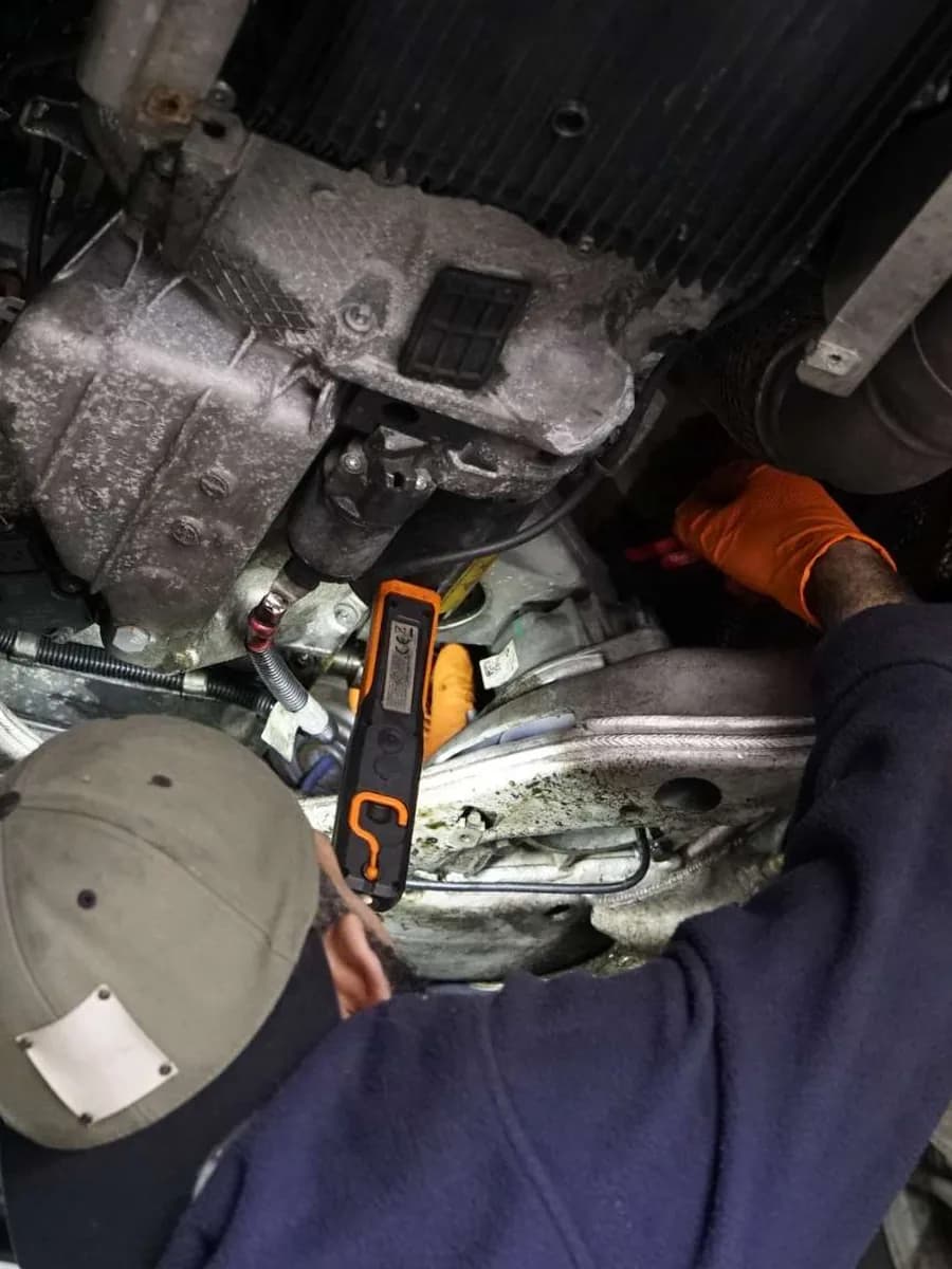 Mechaniker kontrolliert die Unterseite eines angehobenen Fahrzeugs